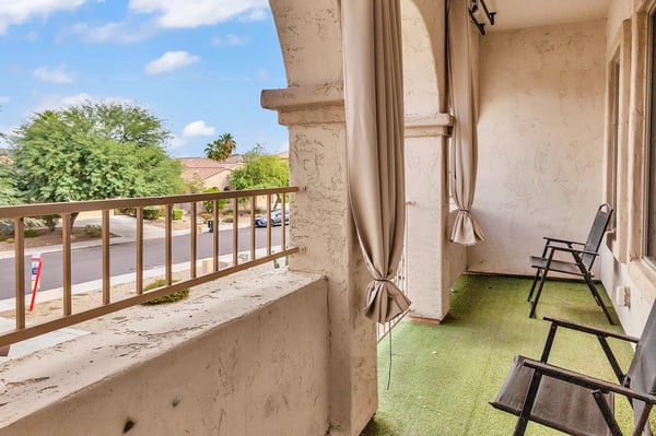 Covered balcony with elegant arches, outdoor curtains, and seating, offering a peaceful outdoor living space to enjoy the Goodyear lifestyle.