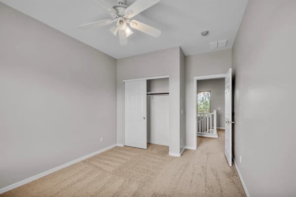 Functional bedroom featuring a closet for storage, neutral finishes, and ceiling fan, offering flexibility for various living needs in Goodyear.