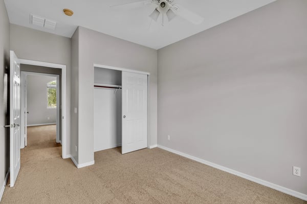 Spacious bedroom with neutral tones, ceiling fan, and soft carpeting, providing a comfortable and adaptable living space in Goodyear.