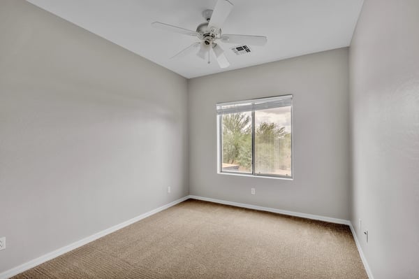 Inviting bedroom filled with natural light, complete with ceiling fan and carpet flooring, perfect for relaxing or guest accommodations in Goodyear.