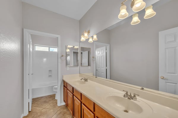 Well-appointed bathroom with dual sinks, large mirror, and wood cabinetry, offering ample storage and functionality in Goodyear.