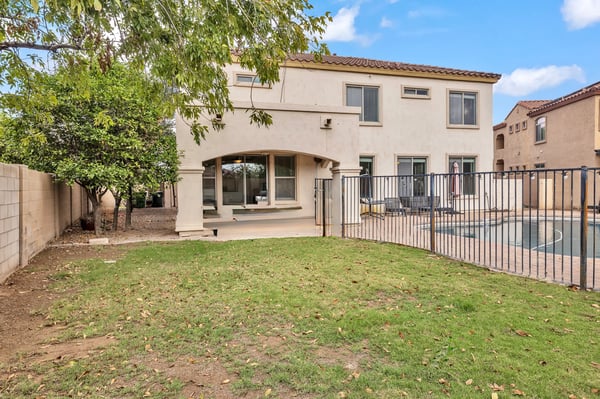 Backyard featuring a grassy area and fenced pool, offering safety and space for outdoor activities in this Goodyear property.