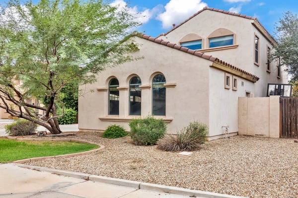 Side exterior featuring desert landscaping, mature greenery, and low-maintenance design for easy living in Goodyear.
