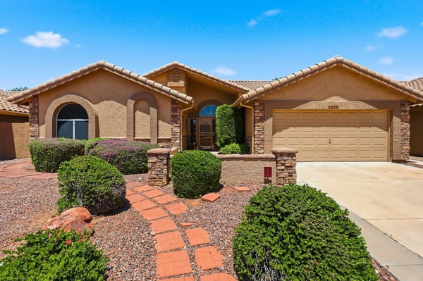 Beautifully landscaped front exterior with stone detailing, mature shrubs, and welcoming pathways enhances the curb appeal of this move-in ready Peoria residence.