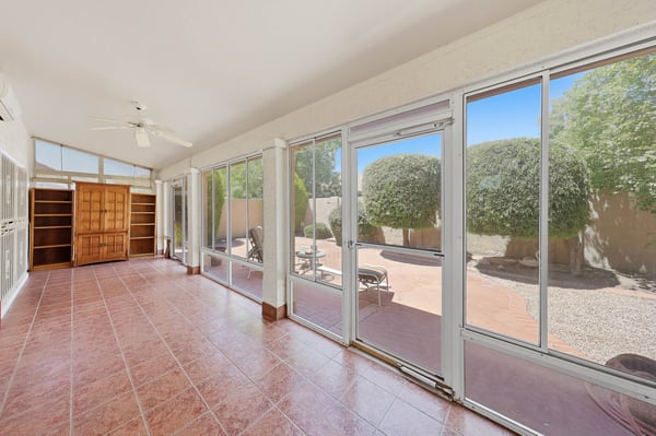 Enclosed Arizona room with expansive windows and private backyard views offers versatile living space ideal for relaxing, hobbies, or entertaining.