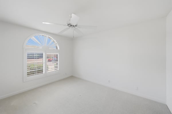 Bright secondary bedroom with plantation shutters and neutral tones offers comfortable guest accommodations or flexible office and hobby space.