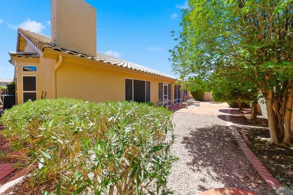 Spacious backyard with mature greenery, gravel landscaping, and inviting patio seating areas offers comfortable outdoor living and entertaining opportunities.