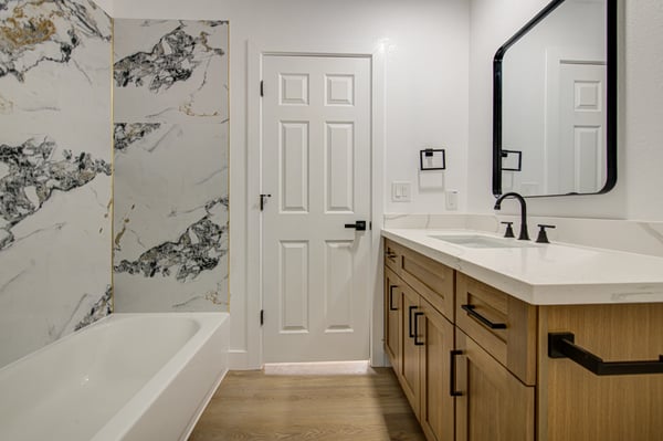 Elegant marble-look tile, a beautifully remodeled tub and shower, quartz countertops, and custom cabinetry combine to create a stylish, move-in-ready bathroom.