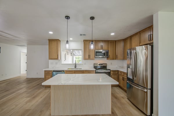 Gather around the oversized island in this beautifully remodeled kitchen featuring elegant white oak cabinetry, quartz countertops, stainless steel appliances, and stylish pendant lighting.