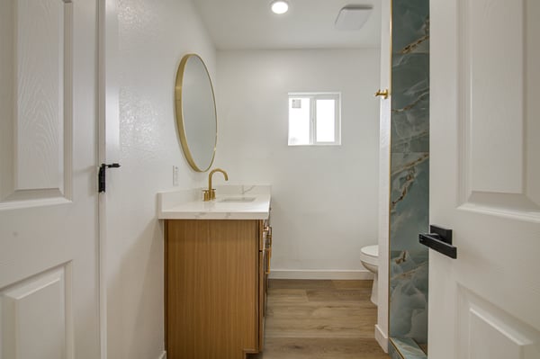 Featuring a quartz vanity, stylish round mirror, modern fixtures, and a beautifully tiled shower, this renovated bathroom combines comfort with contemporary design.