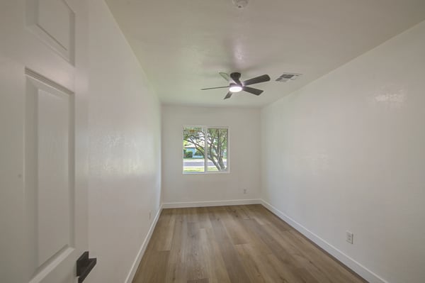 Relax in the spacious primary bedroom featuring updated flooring, modern ceiling fan, fresh interior finishes, and a bright, airy atmosphere in this Buckeye home.