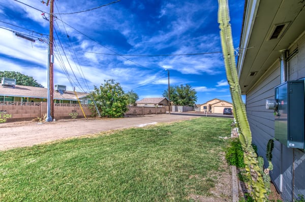 A generous backyard with grassy space and mature landscaping provides plenty of room for outdoor entertaining, pets, gardening, or future backyard enhancements at this Buckeye home.