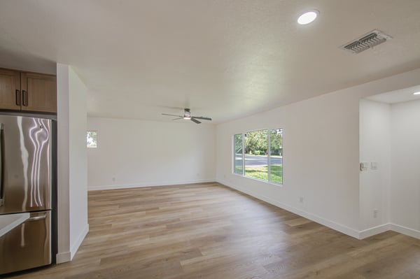 Bright and open, this remodeled living space features contemporary flooring, ceiling fan, recessed lighting, and oversized windows for comfortable everyday living.