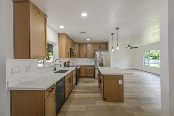 An open-concept design pairs abundant cabinetry, quartz surfaces, stainless steel appliances, and stylish lighting to create the perfect kitchen for cooking and gathering.