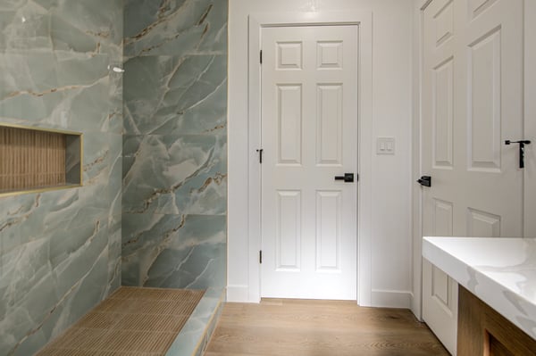 Enjoy a spa-like experience with a custom tiled walk-in shower, built-in bench, recessed niche, elegant vanity, and designer finishes throughout this beautifully remodeled bathroom.