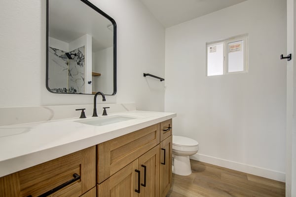 Enjoy modern design with a spacious quartz vanity, custom cabinetry, updated lighting, matte black fixtures, and quality finishes throughout this remodeled bathroom.