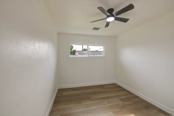 This bright bedroom offers updated flooring, fresh paint, ceiling fan, and natural light, making it ideal as a guest room, office, or additional sleeping space in Buckeye.