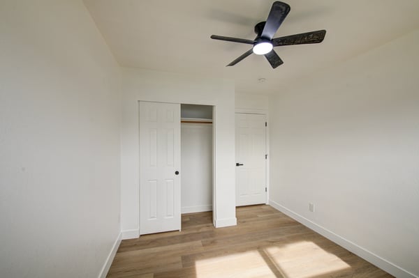 This inviting bedroom features updated flooring, fresh interior finishes, a ceiling fan, and a spacious closet, creating a comfortable space for guests, family members, or a home office.