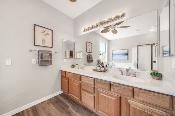 Elegant owner's bathroom with dual sinks, extensive counter space, and abundant storage creates a functional and inviting morning routine. High ceilings and natural light enhance the room's spacious feel.