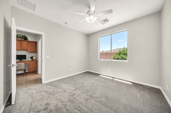 Spacious bedroom filled with natural light from oversized windows and finished with soft carpeting. Perfect as a guest bedroom, home office, or hobby room.