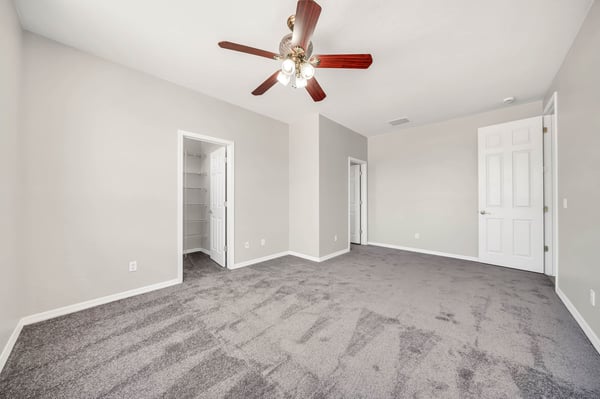 Spacious secondary bedroom with plush carpeting, ceiling fan, and a walk-in closet, offering flexibility for guests, family, or a dedicated workspace. Designed to fit a variety of lifestyle needs.