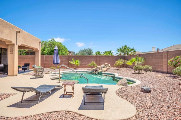 Relax in your private backyard featuring a PebbleTec pool, rock waterfall, covered patio, and easy-care desert landscaping. A perfect setting for outdoor entertaining and everyday enjoyment.