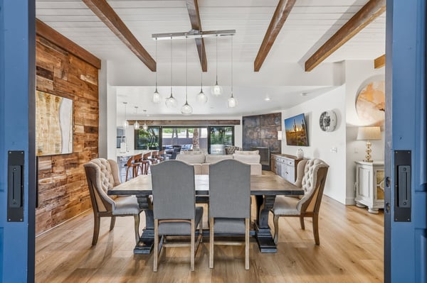 Open dining space connects effortlessly to the living room and kitchen, showcasing vaulted ceilings, exposed beams, designer lighting, and an inviting layout perfect for entertaining.