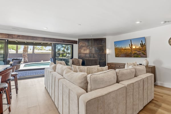 Open great room overlooks the private pool through expansive sliding glass doors, offering seamless indoor-outdoor living with direct access to the gourmet kitchen and entertaining spaces.