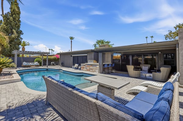 Private backyard retreat features a sparkling pool, spa, outdoor bar, and expansive paver patio with multiple seating areas. Enjoy resort-style living designed for year-round Scottsdale entertaining.