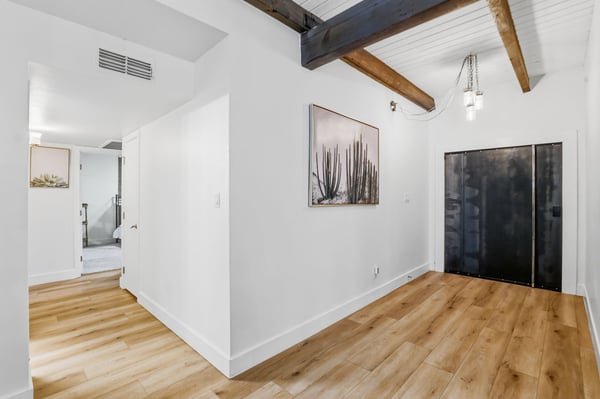 Dramatic entry welcomes guests with vaulted ceilings, exposed wood beams, luxury flooring, and clean architectural lines that define this beautifully renovated Scottsdale home.