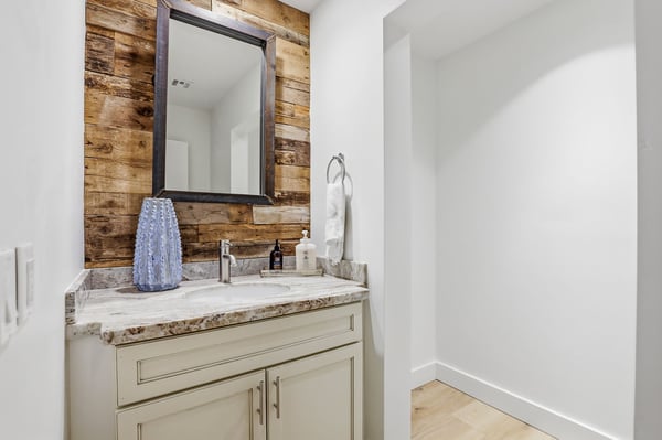Beautifully updated powder room features contemporary fixtures, custom cabinetry, stone countertops, and rustic accent details, offering both style and functionality for guests.