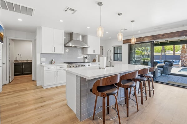 Designed for entertaining, the chef-inspired kitchen offers quartz counters, an oversized island, premium appliances, custom cabinetry, and effortless access to the outdoor living spaces.