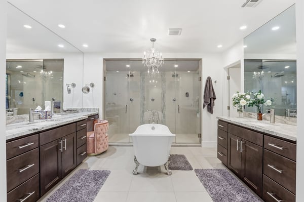 Resort-inspired primary bathroom features a freestanding soaking tub, dual vanities, oversized glass shower, designer chandelier, and upscale finishes that create a luxurious everyday retreat.