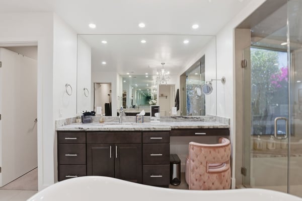 Beautiful vanity space offers dual sinks, stone countertops, custom cabinetry, and a dedicated makeup station, blending luxury and functionality in the spacious primary bathroom.