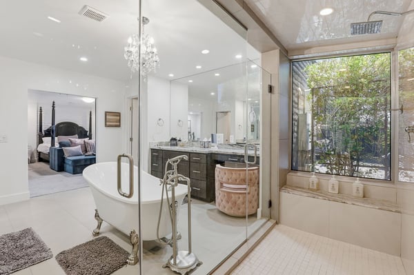 Oversized walk-in shower, freestanding soaking tub, and large windows combine to create a bright, relaxing spa-inspired bathroom with elegant finishes throughout.