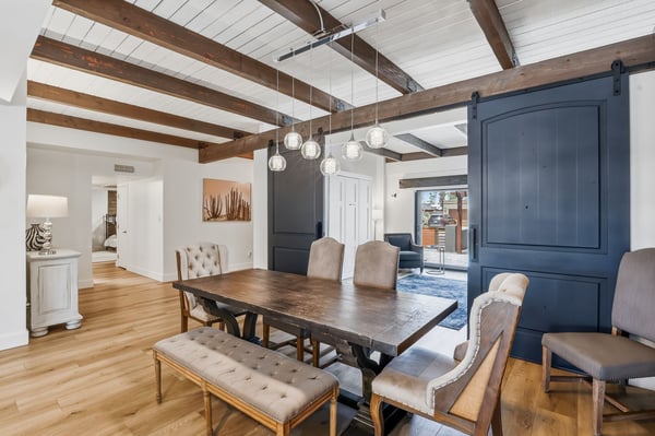 Beautiful dining room features exposed wood beams, sliding barn doors, designer pendant lighting, and luxury flooring, creating an elegant space for everyday meals and entertaining.