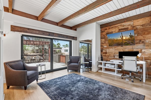 Flexible room is perfect for a home office, media room, or optional fifth bedroom with soaring ceilings, exposed beams, wood accent wall, and access to the outdoor living space.