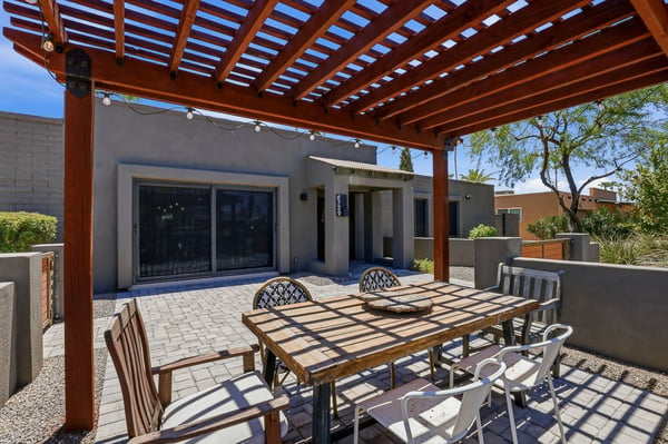 Inviting pergola-covered patio provides shaded outdoor dining and entertaining space with durable pavers and attractive low-maintenance landscaping in this Scottsdale home.
