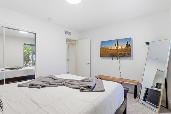 Well-appointed guest bedroom features large windows, mirrored closet doors, plush carpeting, and a bright neutral palette that complements the home's updated interior.