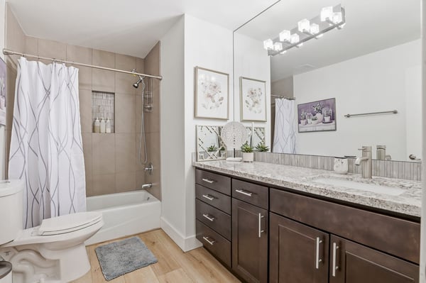 Renovated hall bathroom includes granite countertops, modern vanity, updated lighting, tiled shower and tub surround, and stylish finishes designed for both comfort and convenience.