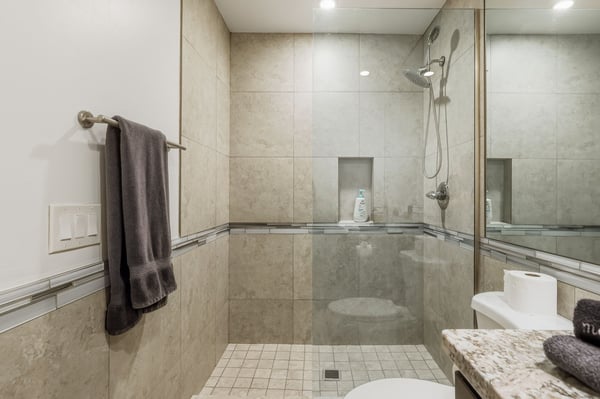 Beautifully updated guest bathroom offers a frameless glass shower, modern tile surround, built-in storage niche, and quality fixtures that enhance everyday living.
