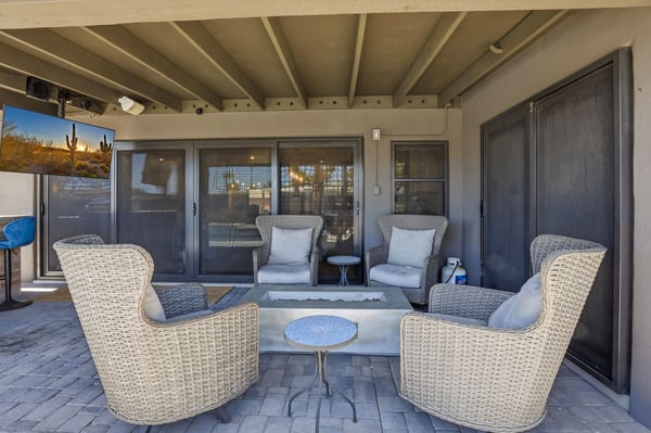 Covered patio is designed for entertaining with comfortable seating, a contemporary fire feature, paver flooring, and easy access to the home's open-concept interior.
