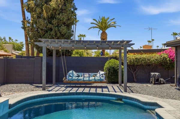 Elegant pergola with suspended daybed swing creates a peaceful outdoor retreat overlooking the pool area. A standout feature that enhances the Scottsdale backyard experience.