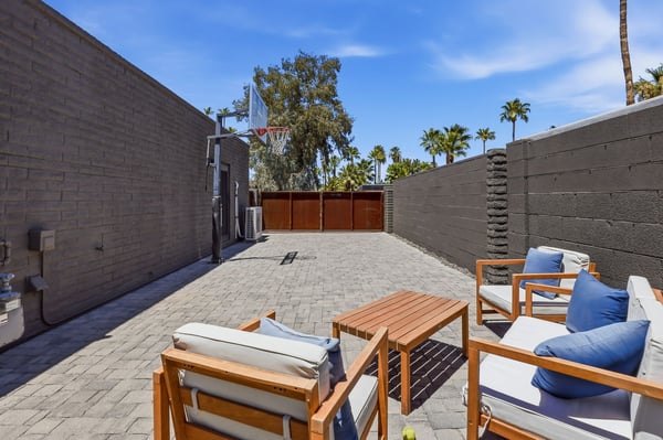 Versatile side yard features paver hardscape, basketball hoop, outdoor seating, and secure gated access, providing additional recreation and entertaining space for this Scottsdale property.