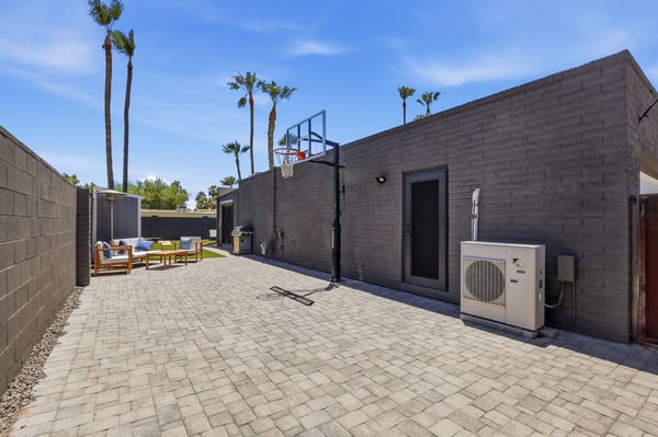 Large paver side yard features a basketball hoop, outdoor seating, and flexible recreation space. This Scottsdale property provides additional room for entertaining and active outdoor living.