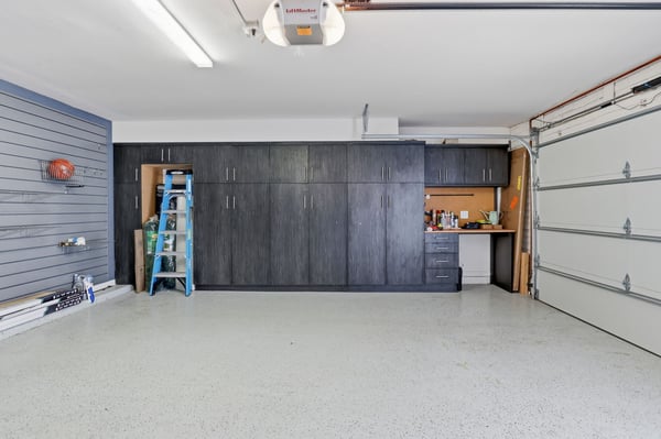 Custom garage organization includes full-height cabinets, integrated workbench, slat wall storage, and durable epoxy flooring, creating an efficient and well-appointed workspace in Scottsdale.