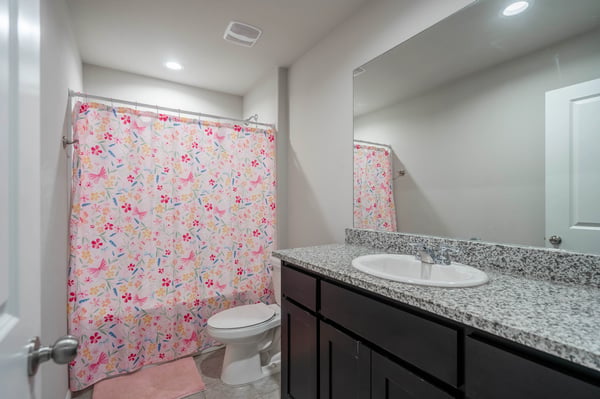 Bright and functional bathroom featuring a modern countertop, floral shower curtain, and ample storage space.