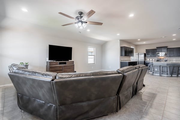 Spacious open-concept living area featuring modern finishes, a ceiling fan, and an inviting kitchen view.