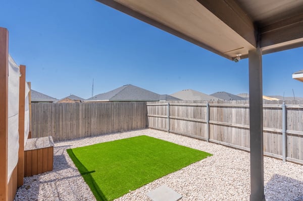 Bright, low-maintenance backyard featuring artificial turf and gravel, perfect for outdoor gatherings and relaxation.