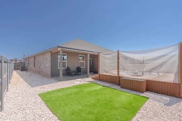 This contemporary home features a spacious yard with synthetic grass and a private outdoor seating area.